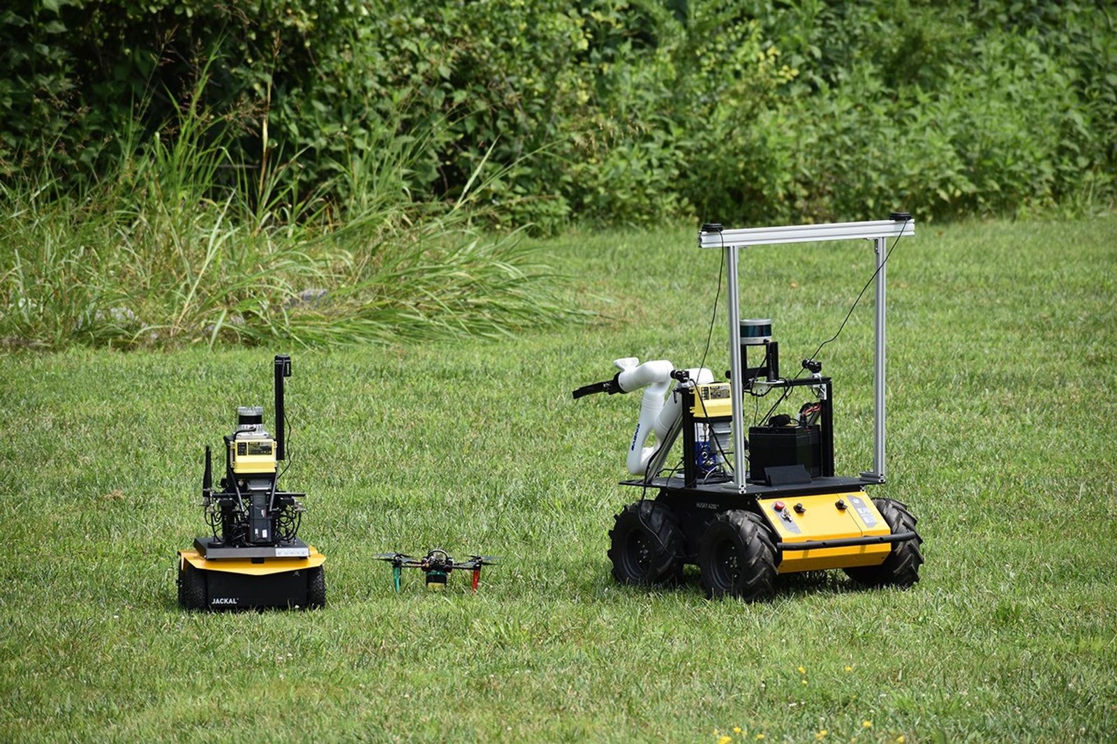 Fotografia oficial da frota ASTRA com um drone ao centro e dois rovers de pesquisa em campo