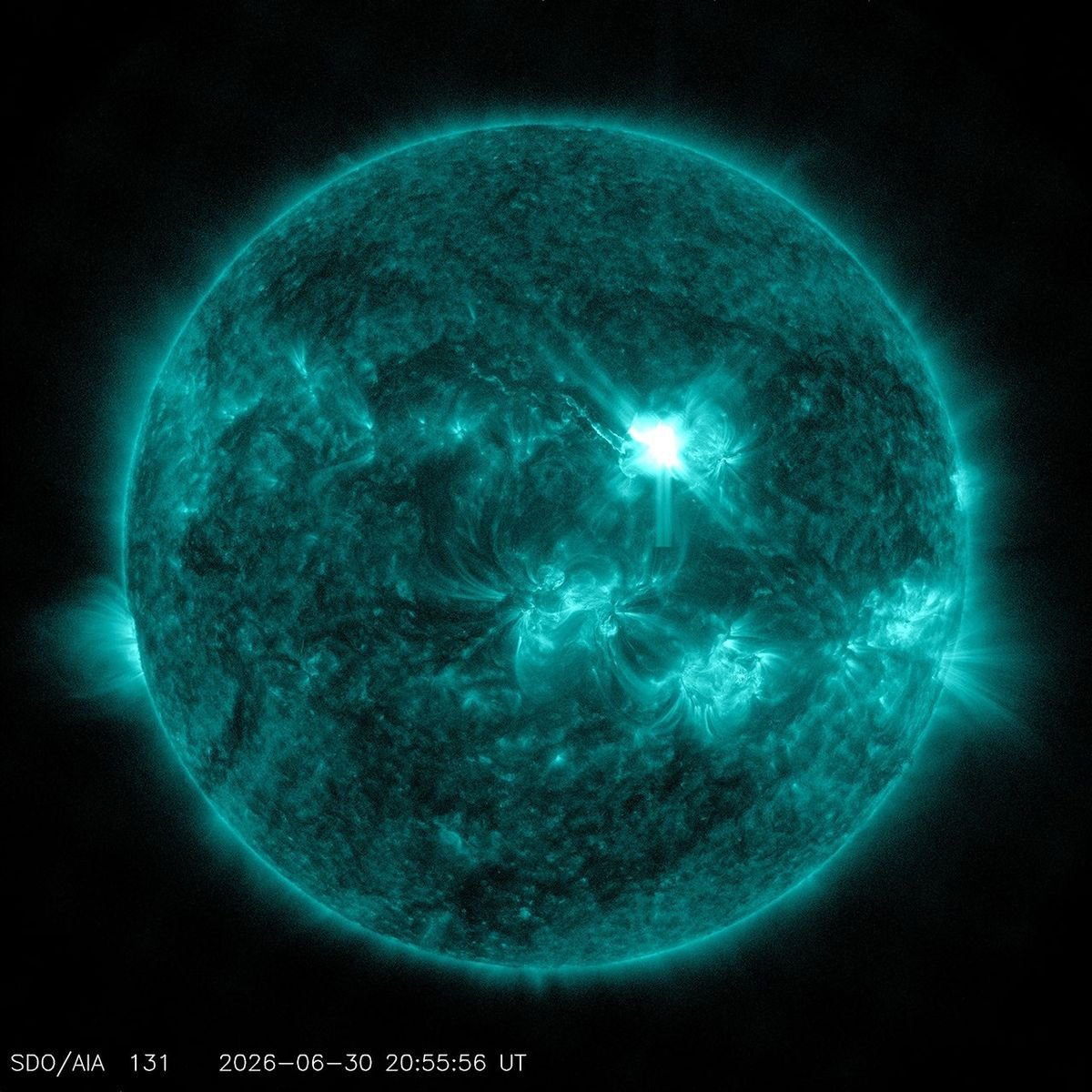 Imagem do Sol em ultravioleta extremo, colorida em azul-esverdeado, com uma erupção brilhante na parte superior direita em 30 de junho de 2026